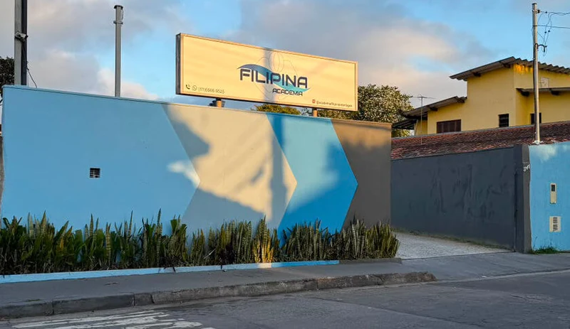 Fachada da Academia Filipina Interlagos, com muro azul e letreiro iluminado na entrada